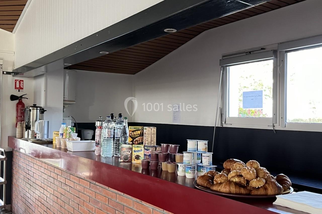 Comptoir en briques avec viennoiseries, boissons et produits alimentaires exposés dans une salle lumineuse.