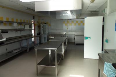 Cuisine professionnelle avec plan de travail en inox, lave-vaisselle industriel et casiers de rangement colorés.
