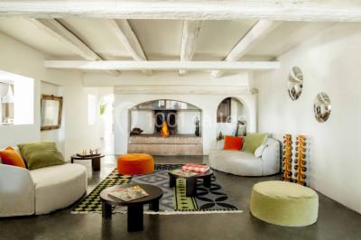 Salon lumineux avec canapé, table basse, tapis à motifs, et chambre en mezzanine avec lit double en arrière-plan.