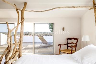 Salon lumineux avec canapé, table basse, tapis à motifs, et chambre en mezzanine avec lit double en arrière-plan.