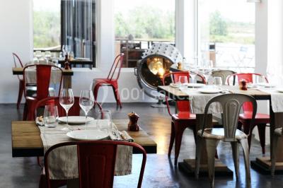 Salon lumineux avec canapé, table basse, tapis à motifs, et chambre en mezzanine avec lit double en arrière-plan.