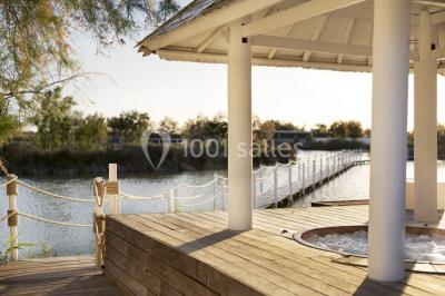 Salon lumineux avec canapé, table basse, tapis à motifs, et chambre en mezzanine avec lit double en arrière-plan.