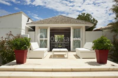 Salon lumineux avec canapé, table basse, tapis à motifs, et chambre en mezzanine avec lit double en arrière-plan.