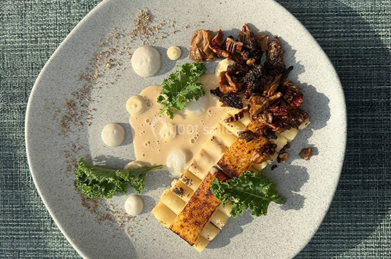 Assiette de pâtes dressées avec une sauce crémeuse, champignons, noix et feuilles de chou kale sur une nappe texturée.