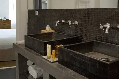 Salon lumineux avec canapé, table basse, tapis à motifs, et chambre en mezzanine avec lit double en arrière-plan.