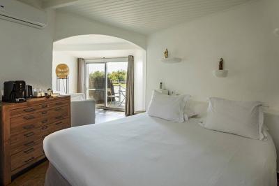 Salon lumineux avec canapé, table basse, tapis à motifs, et chambre en mezzanine avec lit double en arrière-plan.