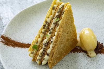 Salon lumineux avec canapé, table basse, tapis à motifs, et chambre en mezzanine avec lit double en arrière-plan.