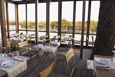 Salon lumineux avec canapé, table basse, tapis à motifs, et chambre en mezzanine avec lit double en arrière-plan.