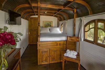 Salon lumineux avec canapé, table basse, tapis à motifs, et chambre en mezzanine avec lit double en arrière-plan.