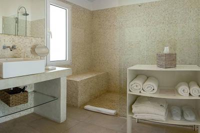 Salon lumineux avec canapé, table basse, tapis à motifs, et chambre en mezzanine avec lit double en arrière-plan.