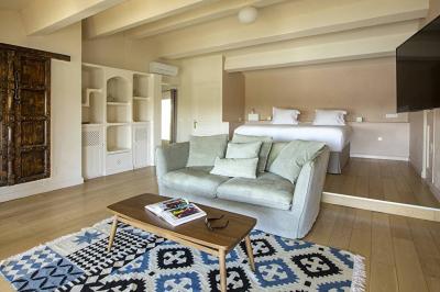 Salon lumineux avec canapé, table basse, tapis à motifs, et chambre en mezzanine avec lit double en arrière-plan.