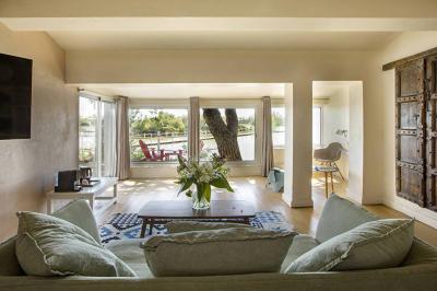 Salon lumineux avec canapé, table basse, tapis à motifs, et chambre en mezzanine avec lit double en arrière-plan.