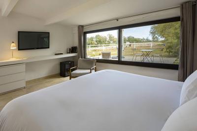 Salon lumineux avec canapé, table basse, tapis à motifs, et chambre en mezzanine avec lit double en arrière-plan.