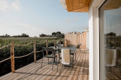 Salon lumineux avec canapé, table basse, tapis à motifs, et chambre en mezzanine avec lit double en arrière-plan.