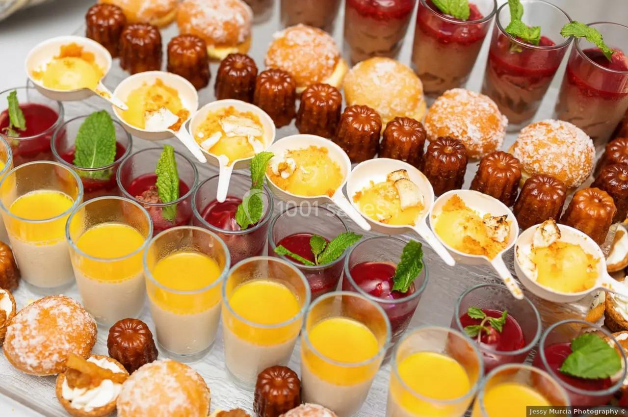 Assortiment de desserts variés comprenant verrines, cannelés, choux garnis et crèmes brûlées, décorés de feuilles de menthe.