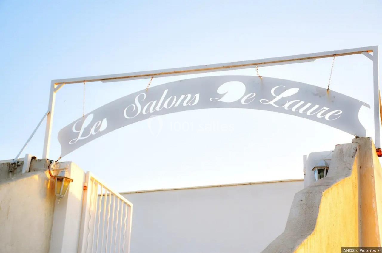 Arche métallique blanche avec l'inscription ’Les Salons De Laure’, surplombant une entrée extérieure.