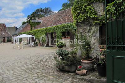 Chaises en bois disposées autour d'une petite table ronde avec un vase, sur une pelouse ensoleillée.