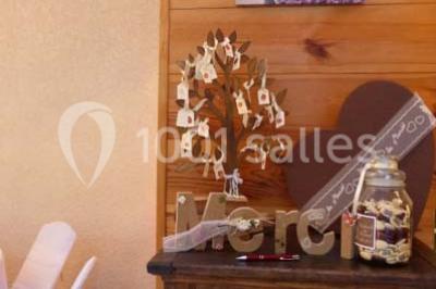 Deux fauteuils en rotin décorés, placés sous une arche ornée de fleurs et de tissus, dans un jardin verdoyant.