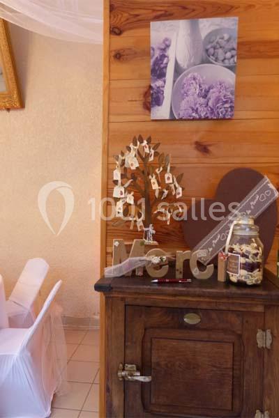 Décoration de mariage avec un meuble en bois, un arbre à vœux, un bocal et des éléments en forme de cœur.