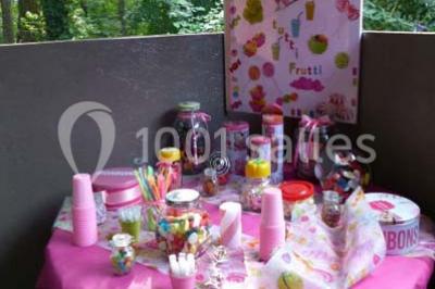 Deux fauteuils en rotin décorés, placés sous une arche ornée de fleurs et de tissus, dans un jardin verdoyant.