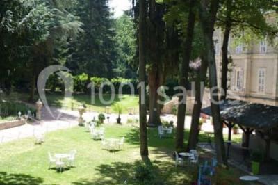 Deux fauteuils en rotin décorés, placés sous une arche ornée de fleurs et de tissus, dans un jardin verdoyant.