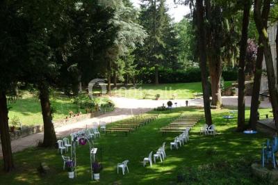 Deux fauteuils en rotin décorés, placés sous une arche ornée de fleurs et de tissus, dans un jardin verdoyant.