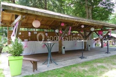 Deux fauteuils en rotin décorés, placés sous une arche ornée de fleurs et de tissus, dans un jardin verdoyant.