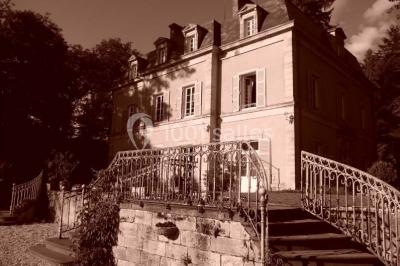 Deux fauteuils en rotin décorés, placés sous une arche ornée de fleurs et de tissus, dans un jardin verdoyant.