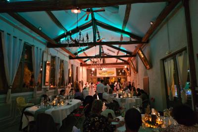 Deux fauteuils en rotin décorés, placés sous une arche ornée de fleurs et de tissus, dans un jardin verdoyant.