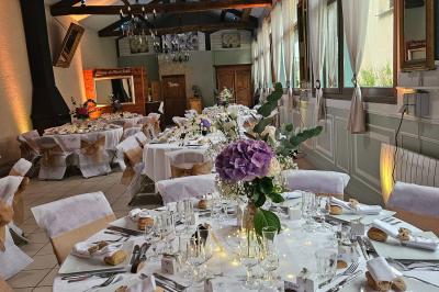 Deux fauteuils en rotin décorés, placés sous une arche ornée de fleurs et de tissus, dans un jardin verdoyant.