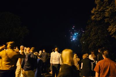 Deux fauteuils en rotin décorés, placés sous une arche ornée de fleurs et de tissus, dans un jardin verdoyant.