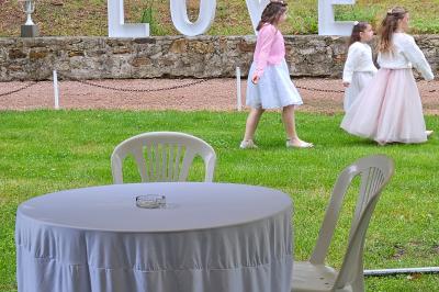Deux fauteuils en rotin décorés, placés sous une arche ornée de fleurs et de tissus, dans un jardin verdoyant.