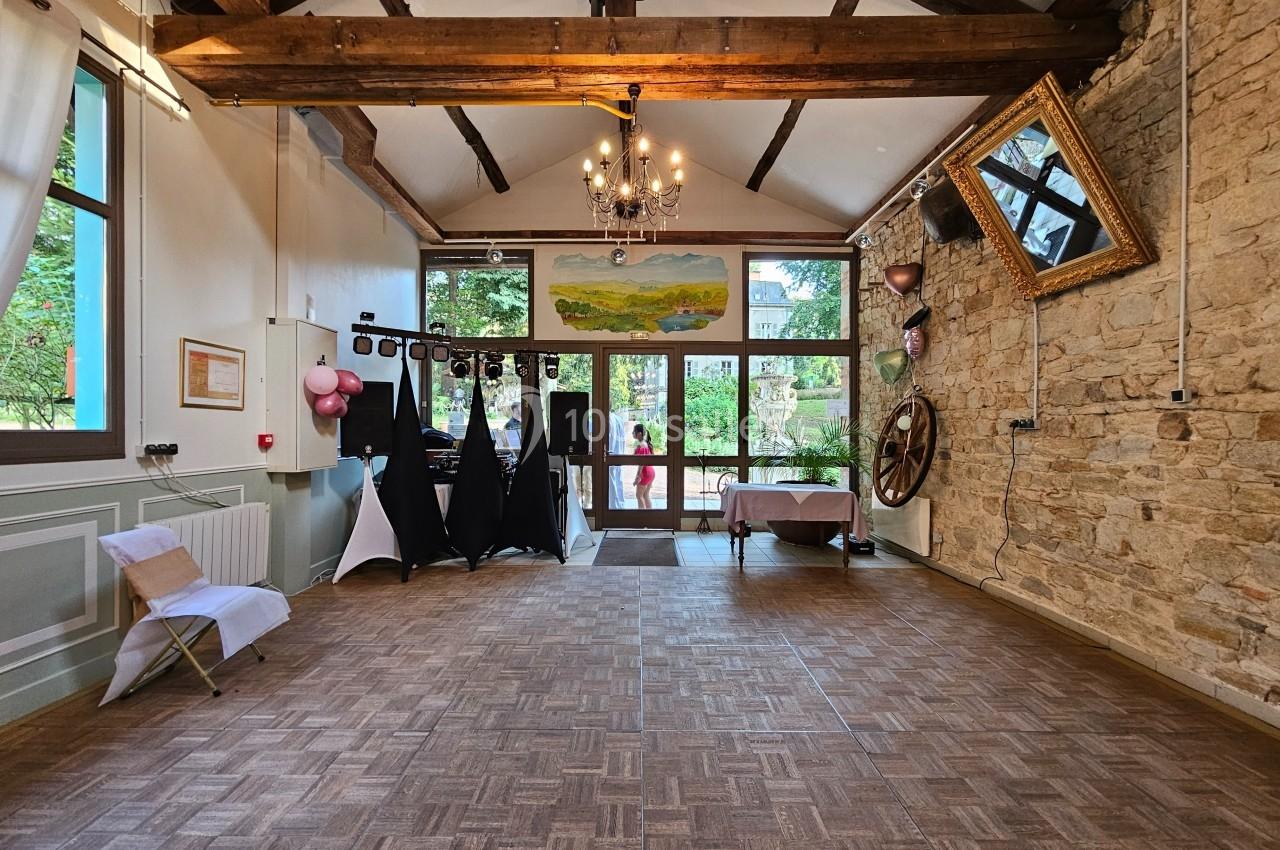 Salle lumineuse avec parquet, poutres apparentes, murs en pierre, décorations festives et grande baie vitrée donnant sur l…