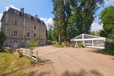 Deux fauteuils en rotin décorés, placés sous une arche ornée de fleurs et de tissus, dans un jardin verdoyant.