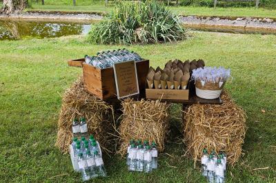 Deux fauteuils en rotin décorés, placés sous une arche ornée de fleurs et de tissus, dans un jardin verdoyant.
