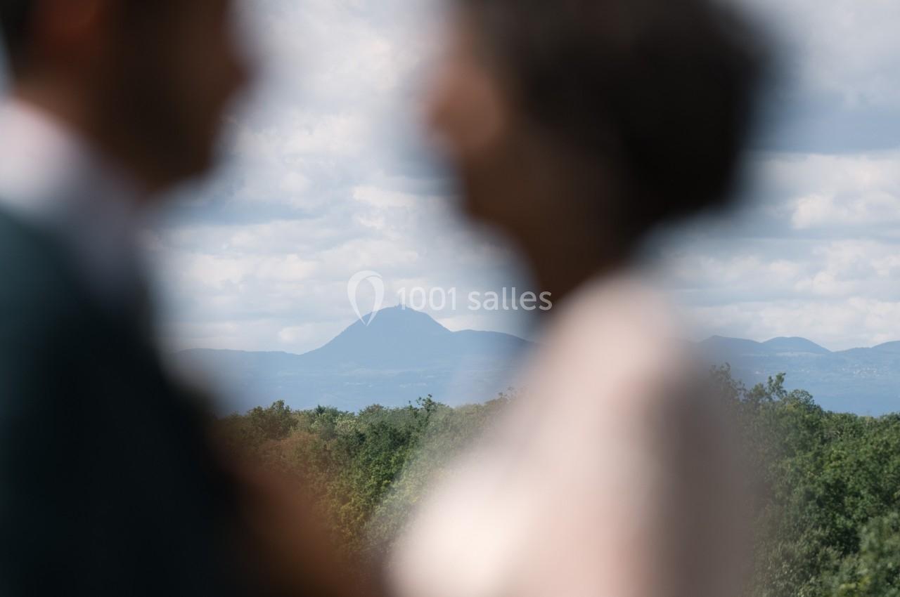Deux silhouettes floues au premier plan avec un paysage de montagne et de forêt en arrière-plan.