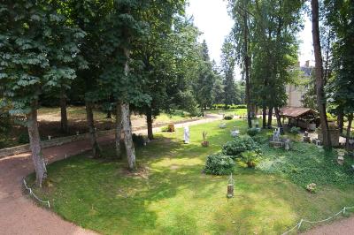 Deux fauteuils en rotin décorés, placés sous une arche ornée de fleurs et de tissus, dans un jardin verdoyant.