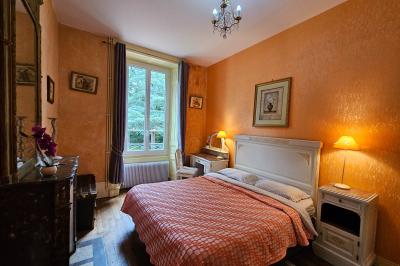 Deux fauteuils en rotin décorés, placés sous une arche ornée de fleurs et de tissus, dans un jardin verdoyant.