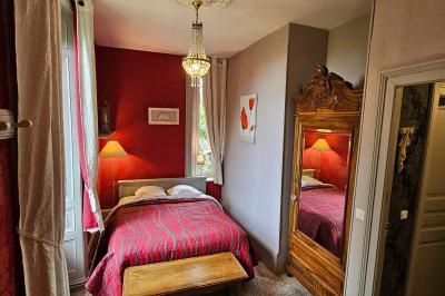 Deux fauteuils en rotin décorés, placés sous une arche ornée de fleurs et de tissus, dans un jardin verdoyant.