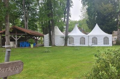 Deux fauteuils en rotin décorés, placés sous une arche ornée de fleurs et de tissus, dans un jardin verdoyant.