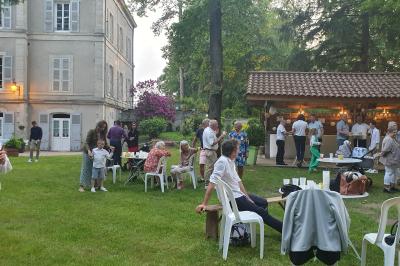 Deux fauteuils en rotin décorés, placés sous une arche ornée de fleurs et de tissus, dans un jardin verdoyant.