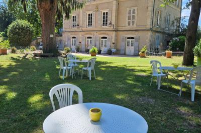 Deux fauteuils en rotin décorés, placés sous une arche ornée de fleurs et de tissus, dans un jardin verdoyant.
