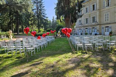 Deux fauteuils en rotin décorés, placés sous une arche ornée de fleurs et de tissus, dans un jardin verdoyant.