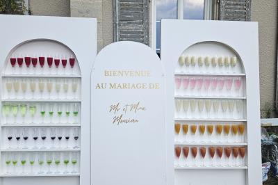 Deux fauteuils en rotin décorés, placés sous une arche ornée de fleurs et de tissus, dans un jardin verdoyant.