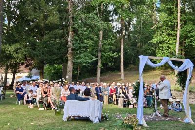 Deux fauteuils en rotin décorés, placés sous une arche ornée de fleurs et de tissus, dans un jardin verdoyant.