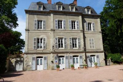 Espace couvert avec canapé, tables et chaises en bois, entouré de verdure visible à travers les ouvertures.