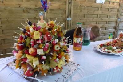 Espace couvert avec canapé, tables et chaises en bois, entouré de verdure visible à travers les ouvertures.