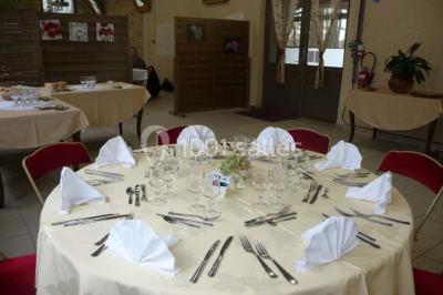Espace couvert avec canapé, tables et chaises en bois, entouré de verdure visible à travers les ouvertures.