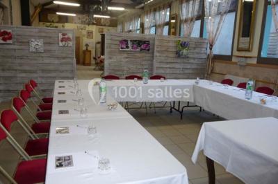 Espace couvert avec canapé, tables et chaises en bois, entouré de verdure visible à travers les ouvertures.