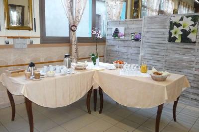 Espace couvert avec canapé, tables et chaises en bois, entouré de verdure visible à travers les ouvertures.